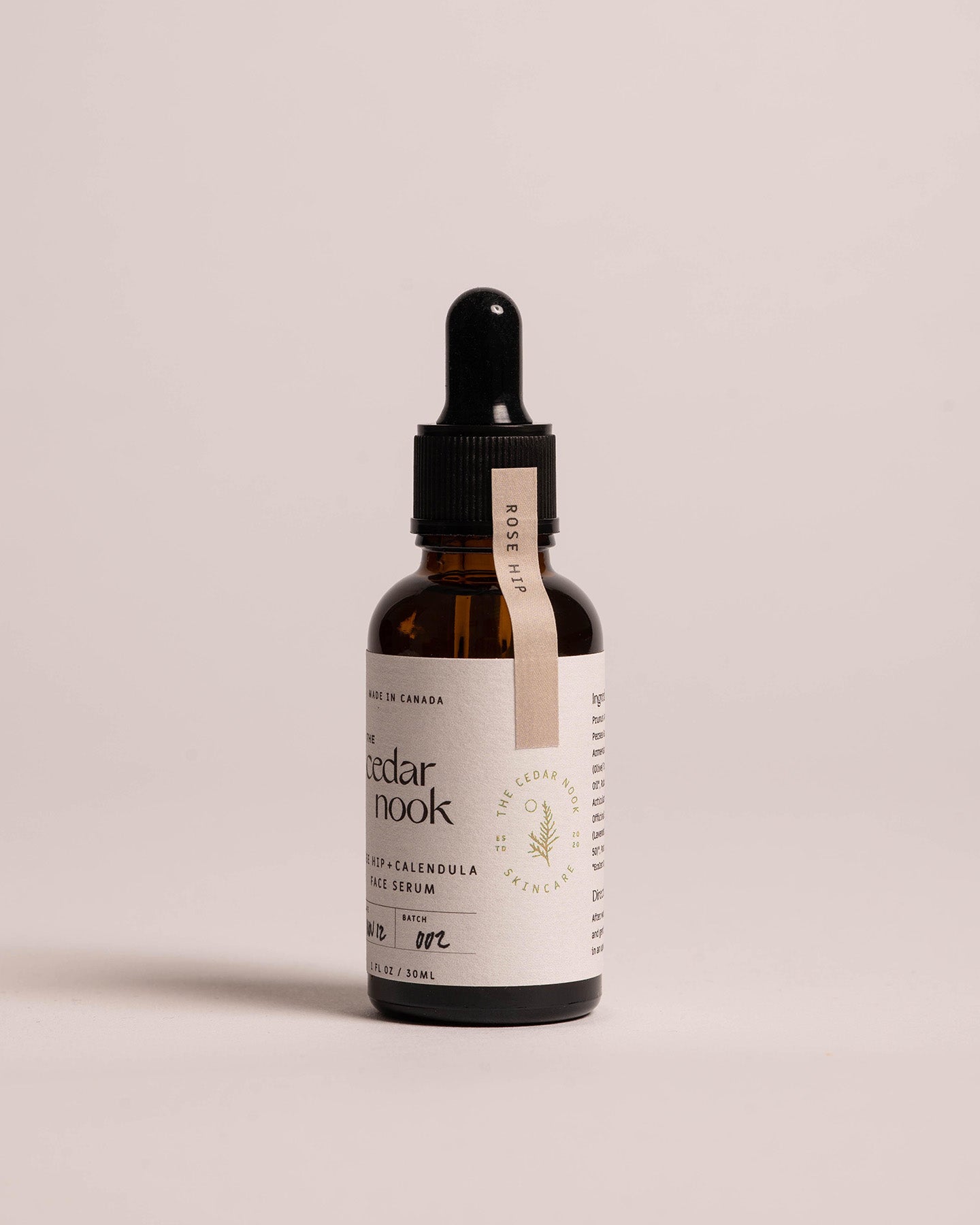 Side view of the Rose Hip and Calendula Face Serum in a 1 oz amber glass dropper bottle, white label and pink safety seal | The Cedar Nook
