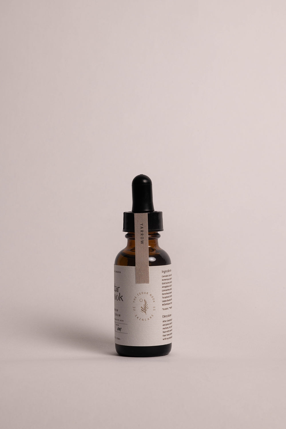 The Cedar Nook | Yarrow Face Serum for dry and sensitive skin in an amber glass bottle with dropper side view, showing light pink safety seal and forest green logo