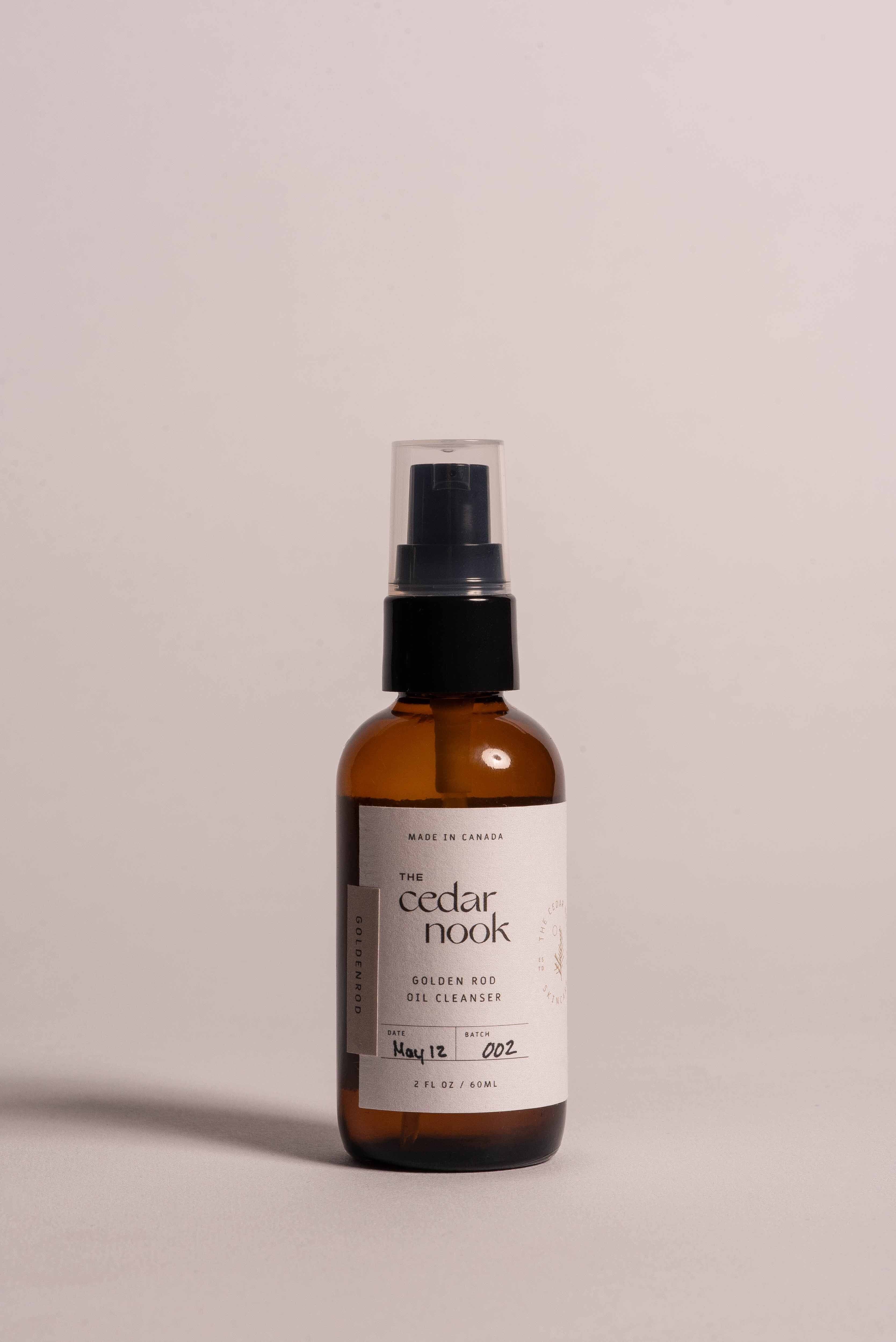The Cedar Nook Goldenrod Oil Cleanser in 2 oz reusable amber glass bottle with airless pump top showing front label on light pink background