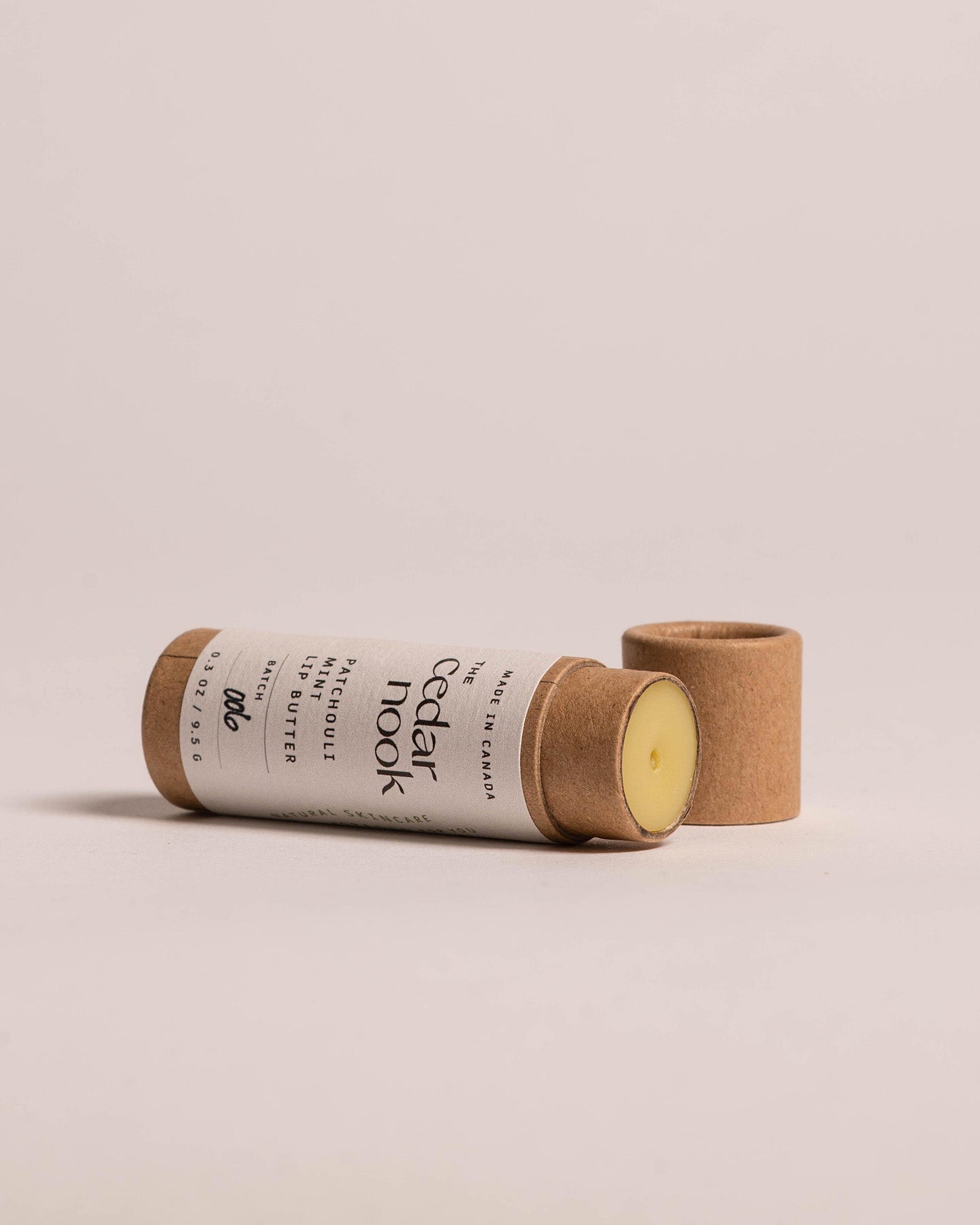 Patchouli Mint Lip Butter | The Cedar Nook in a kraft compostable tube on it's side with the lid off, showing the top of the lip butter in a push tube